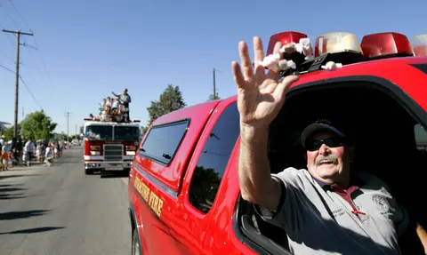 A man in a fire vehicle throws candy at a parade.