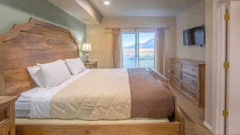 A bedroom interior featuring a large wooden bed and a view outside.