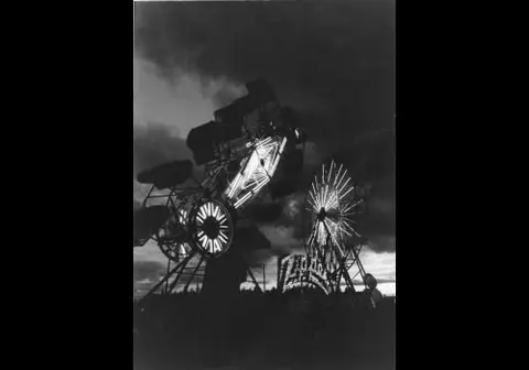 Black and white photograph showing carnival rides at night.