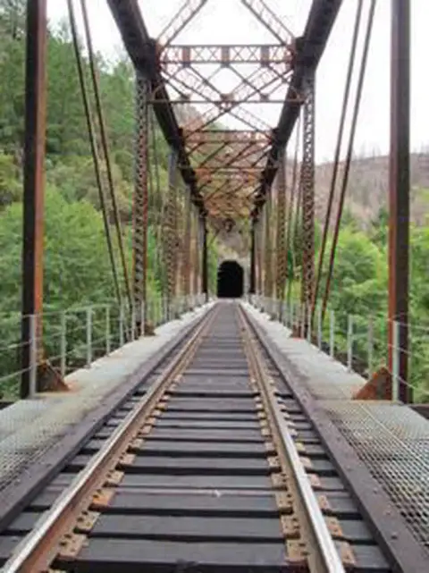 A railroad bridge leading to a tunnel.