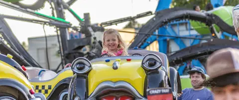 A young girl smiling while riding an amusement park ride.