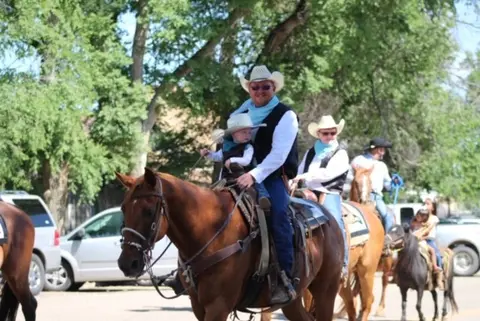 People riding horses down a street in a parade.