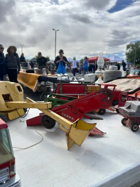 A collection of vintage toy trucks and construction vehicles displayed on a table at an outdoor market.