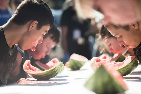 People participate in a watermelon eating contest.