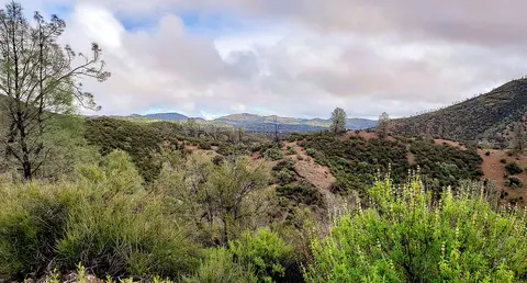 A scenic view of rolling hills and trees under a cloudy sky.