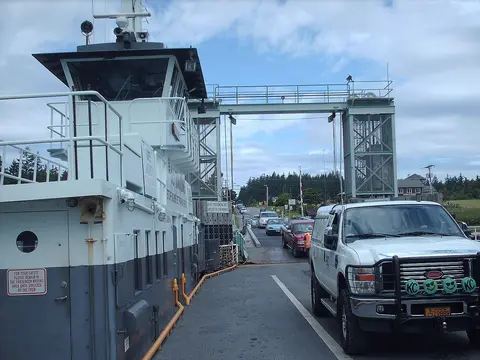 A vehicle ferry docked with cars waiting to board.