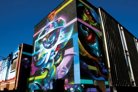 A colorful mural painted on the side of a building under a blue sky.