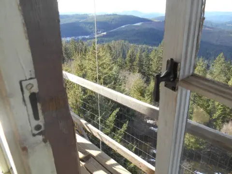 A view of forested mountains from inside a building through an open window.