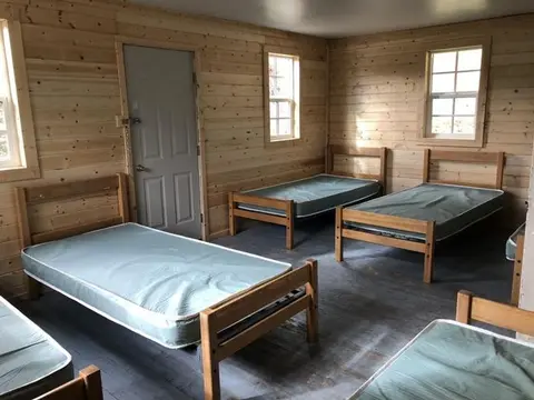 Interior view of a rustic wooden room furnished with several single beds.