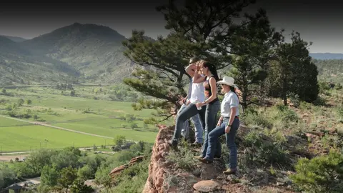 A group of people standing on a rocky outcrop overlooking a valley.