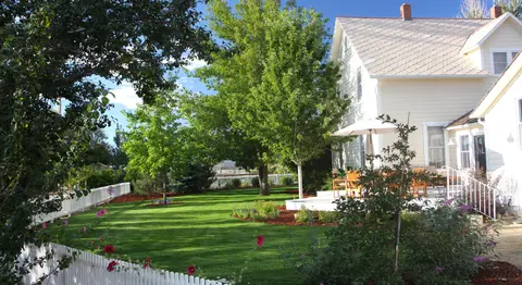 An exterior view of a two-story house with a large green lawn and trees.