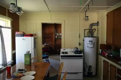 An interior view of a rustic kitchen with wooden cabinets and appliances.