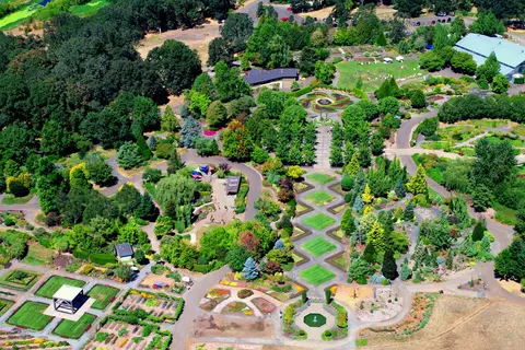 An aerial view of a large landscaped garden with paths, lawns, trees, and flower beds.