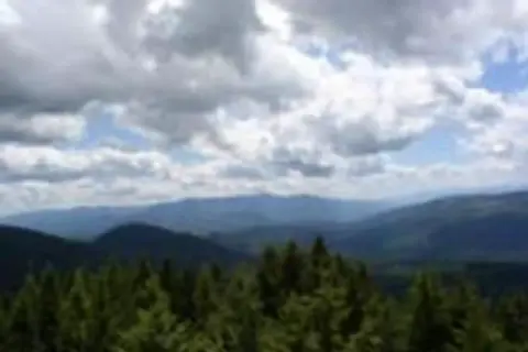 A view of forested mountains under a cloudy sky.