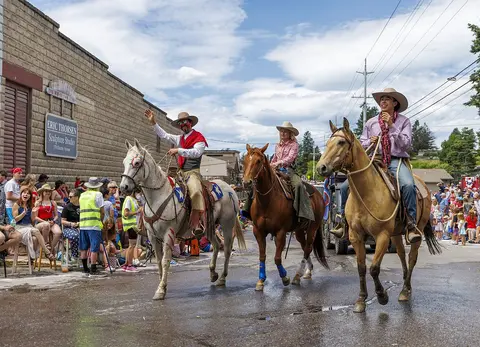 People ride horses down a street during an outdoor event.