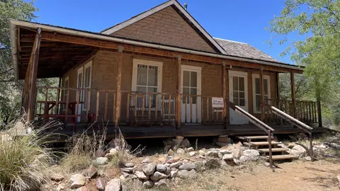 An old adobe house with a covered porch outdoors.