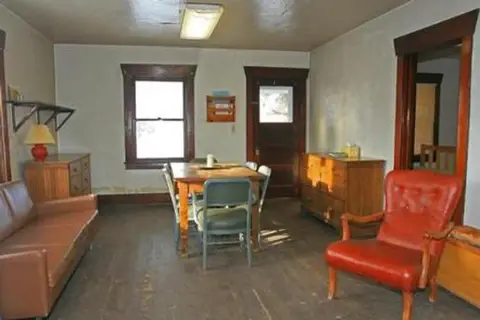 An interior view of a furnished room with a wooden table, chairs, sofa, and a red armchair.