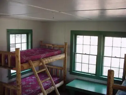 An interior room with bunk beds and windows with green frames.