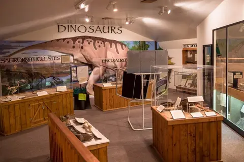 An interior view of a museum exhibit featuring dinosaur displays and murals.
