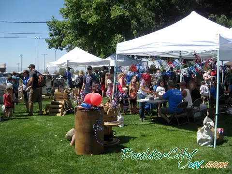 A photo of an outdoor community event with tents, booths, and people gathered on grass.