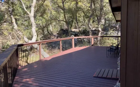 A large wooden deck overlooks a wooded hillside.