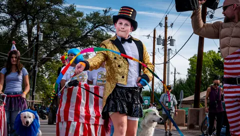 A person dressed as a ringmaster participates in an outdoor parade.