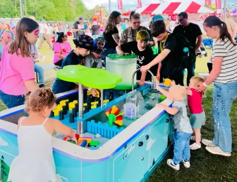Children play with a water table at an outdoor event.