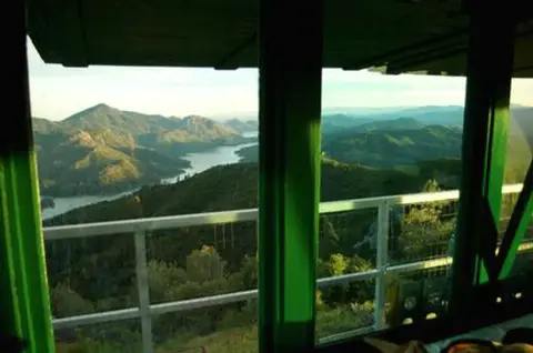 Looking out from inside a lookout tower at mountains and water below.