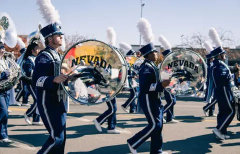 A marching band in blue uniforms performs in a parade.