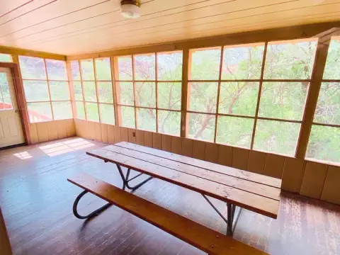 A screened-in porch with a wooden picnic table.