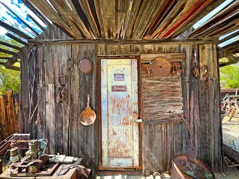An old wooden building wall decorated with weathered tools and a door.