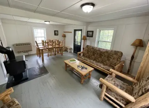 An interior view of a rustic room with wooden furniture and a stove.