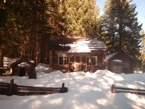 A log cabin surrounded by snow and trees.