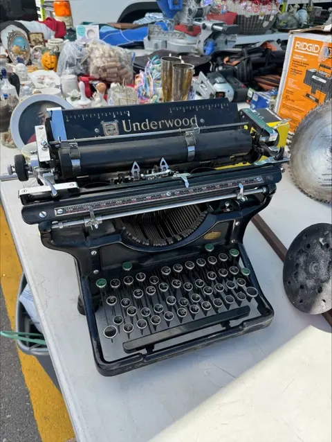 An old black Underwood typewriter sits on a table at a flea market.