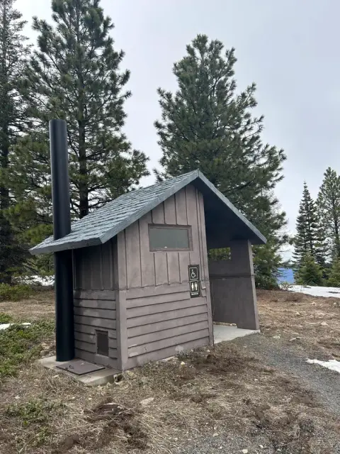 An outdoor restroom building stands in a forest area.