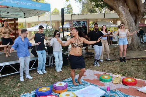 A group of people dancing together outdoors near a stage.