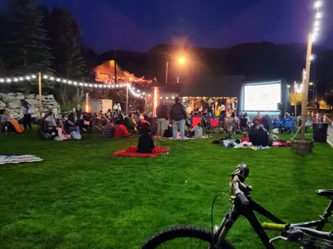 People gathered on a lawn at night for an outdoor movie screening.