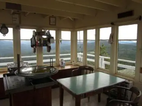 Interior view of a fire lookout tower with windows looking out over a landscape.