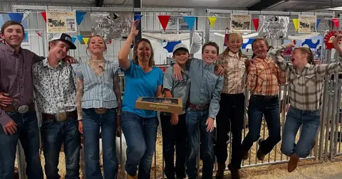 A group of young people and a woman smiling and posing together indoors.
