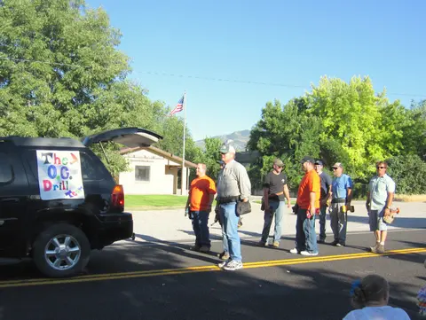 A group of men standing near an SUV with a sign on the back window.