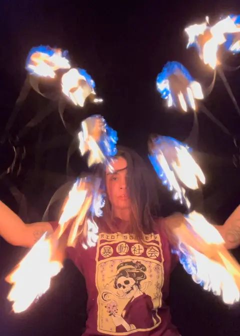 A person performs with fire against a dark background.
