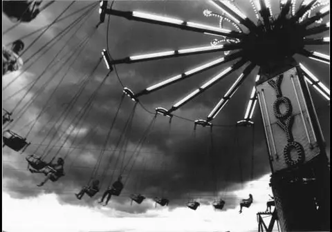 A black and white photograph of a swing ride at a carnival.