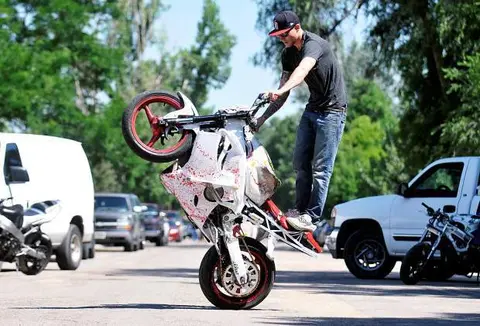 A person performs a stunt on a motorcycle outdoors.