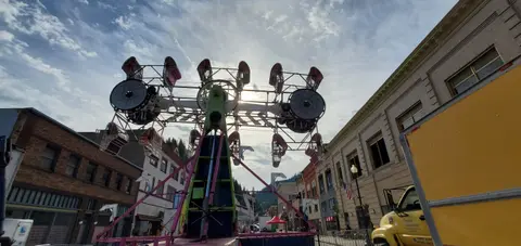 An amusement ride set up on a street between buildings.