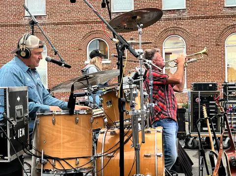 A band performs outdoors in front of a brick building.