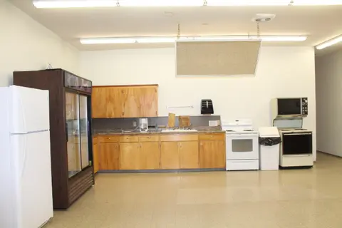 A spacious breakroom or kitchen area with multiple refrigerators, counters, and stoves.