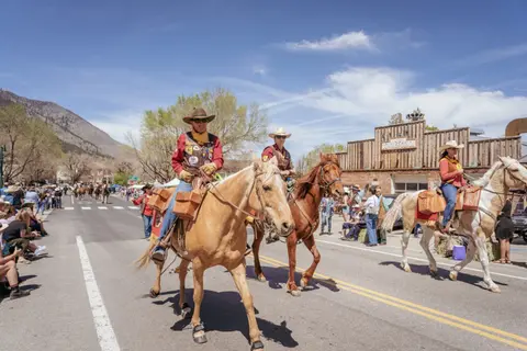 People ride horses down a street during an outdoor event.