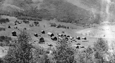 Historic black and white aerial photograph of a settlement with wooden buildings in a valley.