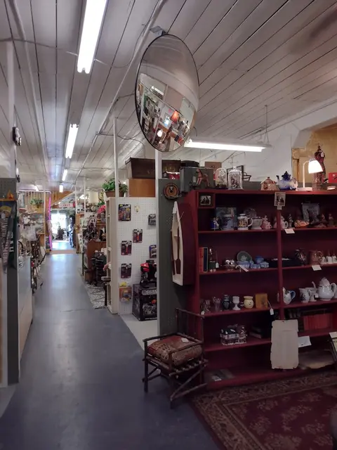 An interior view of a store displaying shelves of goods and a convex security mirror on the ceiling.