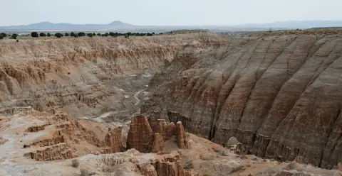 A view of eroded cliffs and canyons in a desert landscape.
